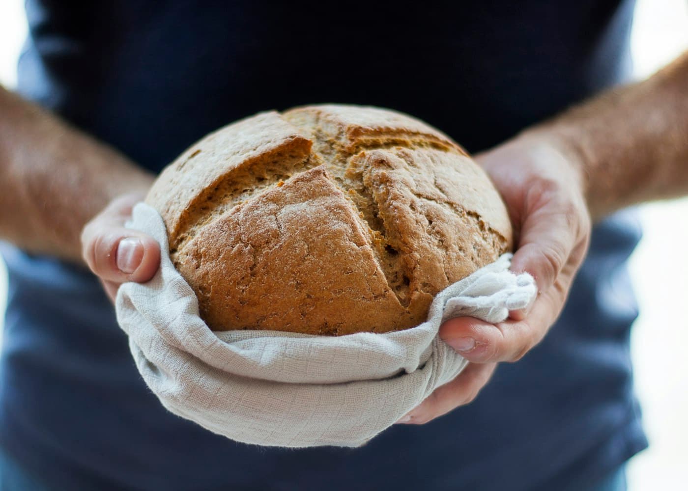 A baker holding a fresh loaf of sourdough