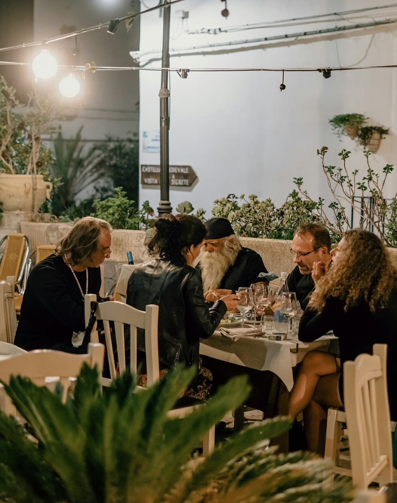 People eating together at an outdoor restaurant strung with lights